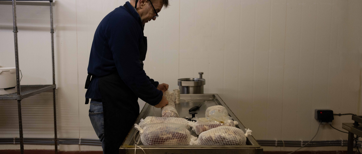 Charcuterie being prepared and hung in the curing room at Beal's Farm