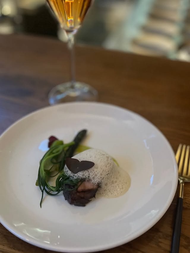 Plated Mangalitsa course with a glass of orange wine